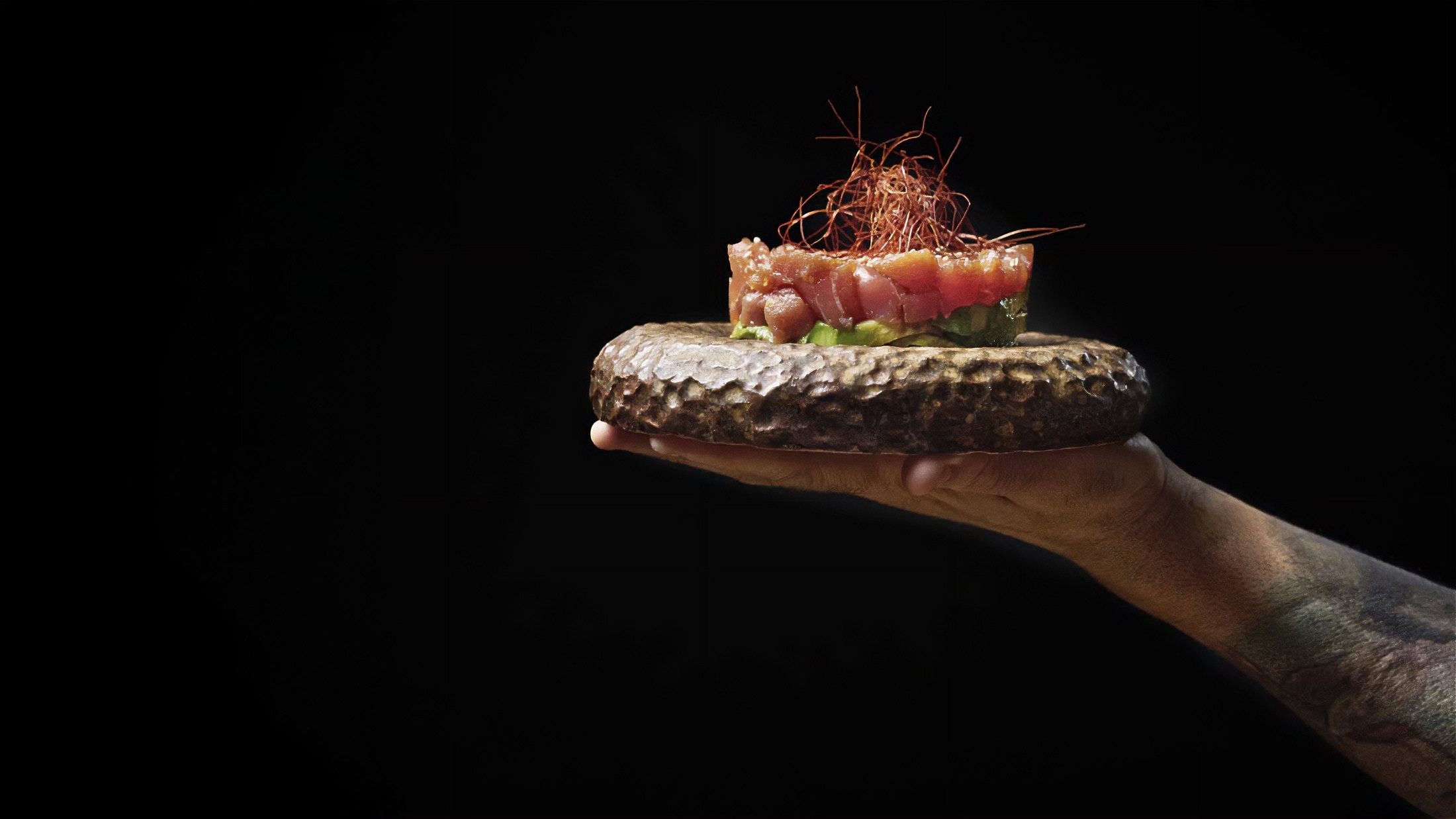 Fotografía gastronómica para Muesca con plato sostenido sobre fondo oscuro